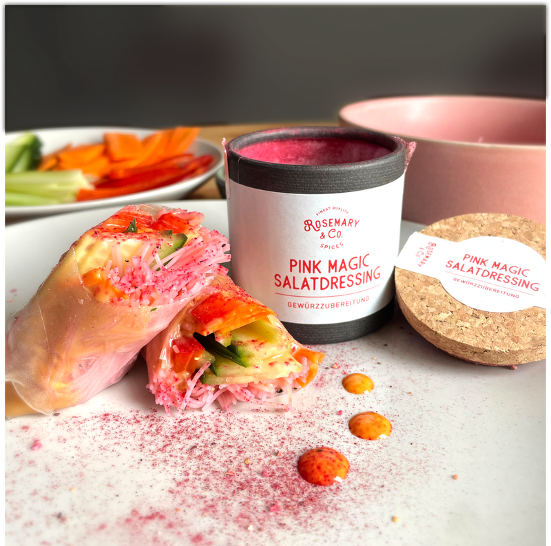 Frühlingsrollen mit pinkem Dressing neben einer geöffneten Pappdose "Pink Magic Salatdressing" auf einem Teller.
