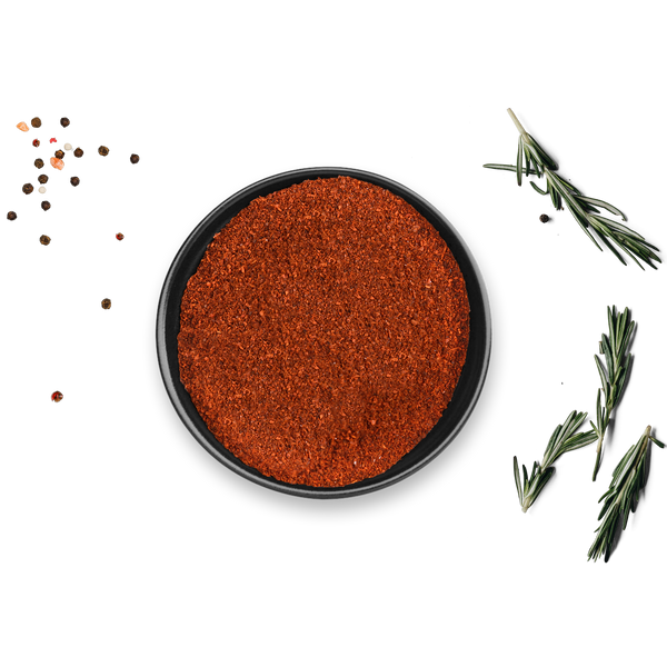 Auf weißem Untergrund steht eine schwarze Schale mit Bio Paprika Geräuchert von Rosemary & Co. Gewürze, umgeben von verstreuten Pfefferkörnern und Rosmarinzweigen.