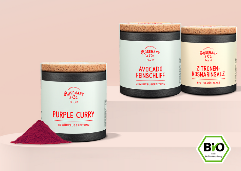 Drei Gewürzdosen mit Korkdeckel: Purple Curry, Avocado Feinschliff, Zitronen-Rosmarinsalz, daneben ein Bio-Label.