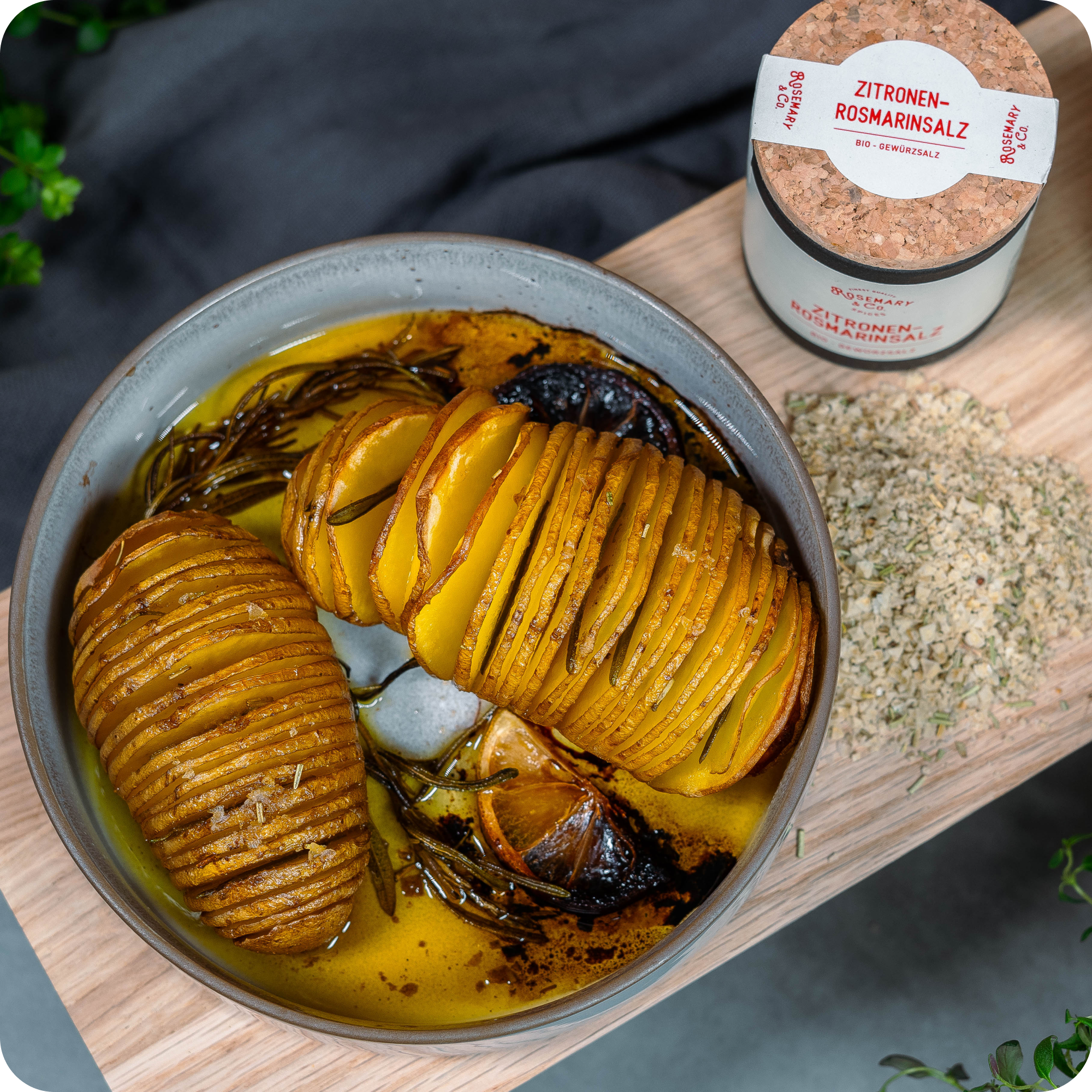 Schale mit Hasselback-Kartoffeln und Zitrone, daneben Dose Zitronen-Rosmarinsalz Bio von Rosemary & Co.