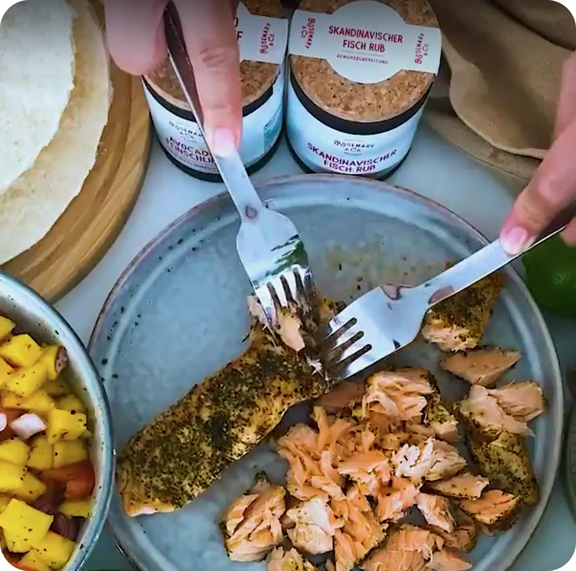 Hände zerteilen Fisch mit Gabeln, gewürzt mit Rosemary & Co. Skandinavischer Fisch Rub, daneben Salsa und Tortillas