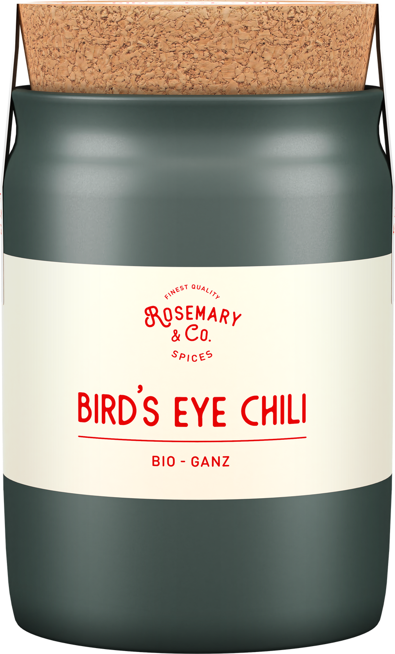 Dose mit Korkdeckel, Aufschrift Rosemary & Co., Bio Bird's Eye Chili, Keramiktopf im Hintergrund1
